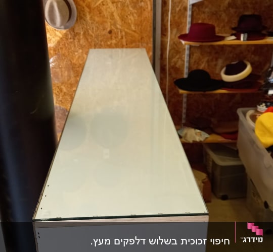 משטח זכוכית על גבי דלפק לבן בחנות כובעים